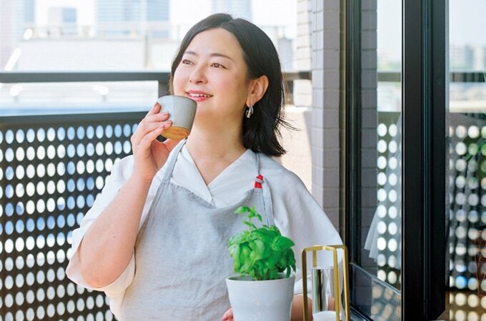 ベランダで湯飲みを片手に外を眺める女性