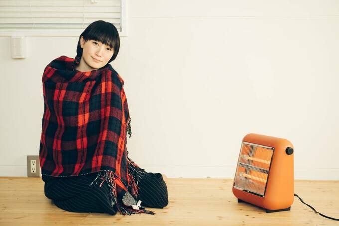 ストーブの前で毛布にくるまる女性