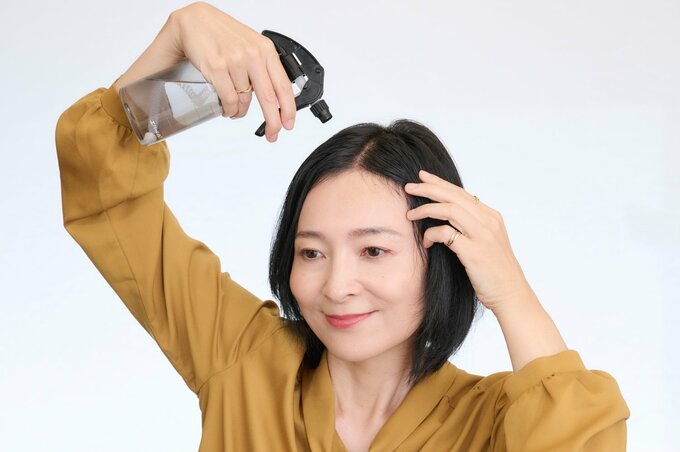 髪にスプレーをかける女性
