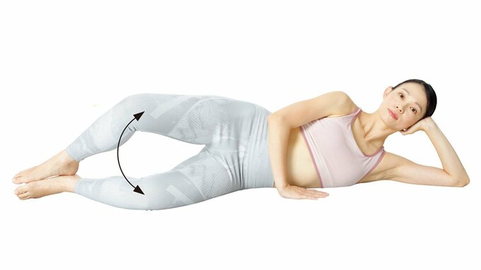 床に横たわってひじをつき、かかとをつけたままひざを開いている女性