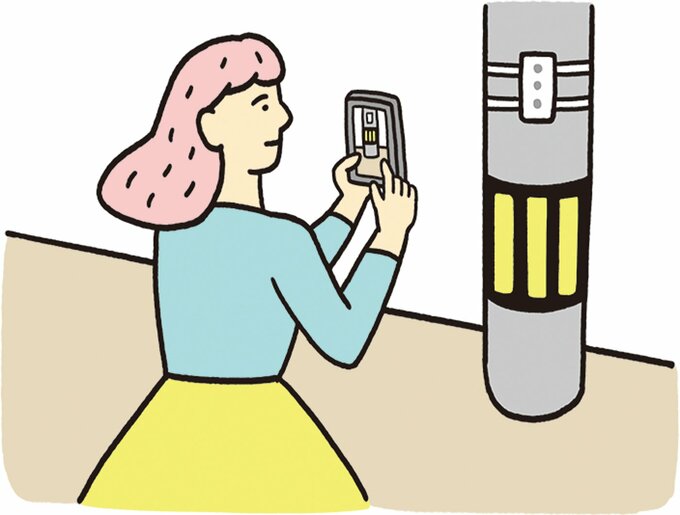 電柱をスマホで撮影する女性