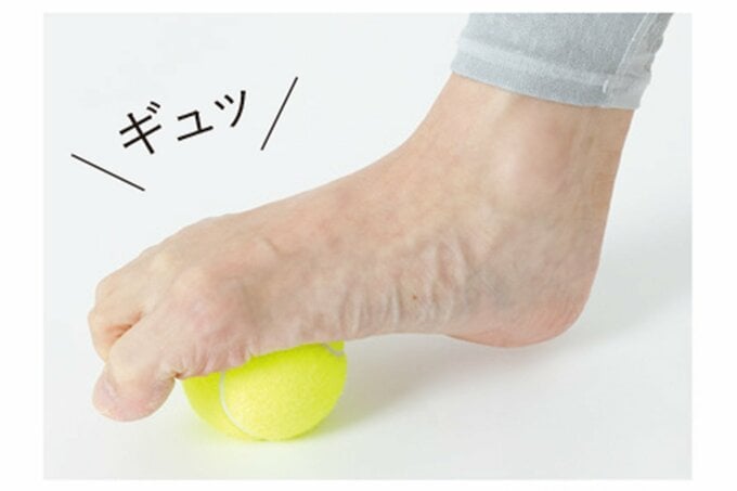 足の親指でボールをつかむようにテニスボールを転がしている