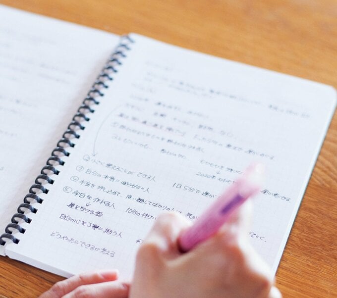 ノートにペンで文字を書き込む手