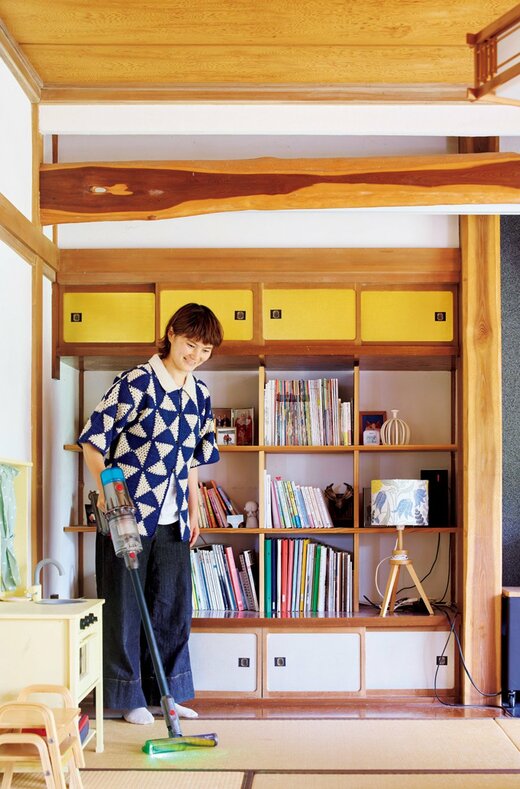 畳の部屋で掃除機をかける女性