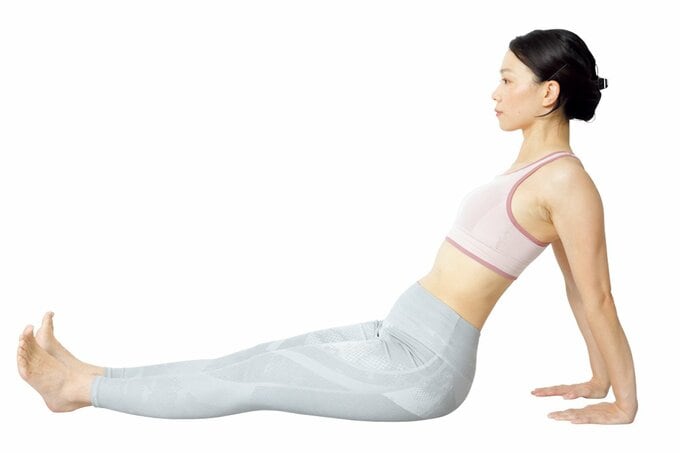 脚を伸ばして座り、お尻の少し後ろに手をついている女性