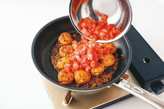 フライパンにトマトを入れる様子