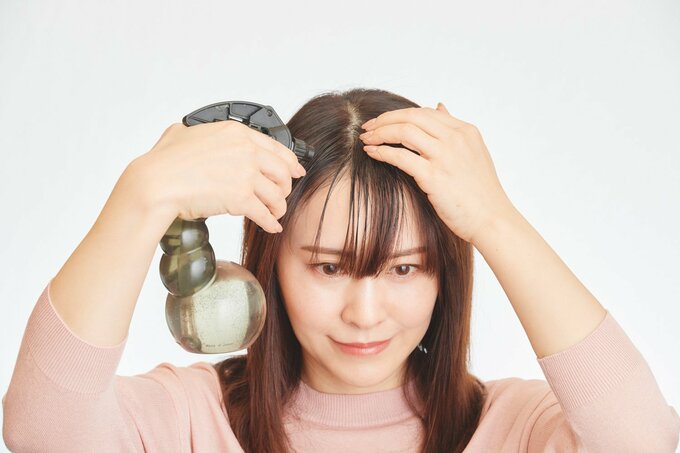 前髪に水スプレーをする女性