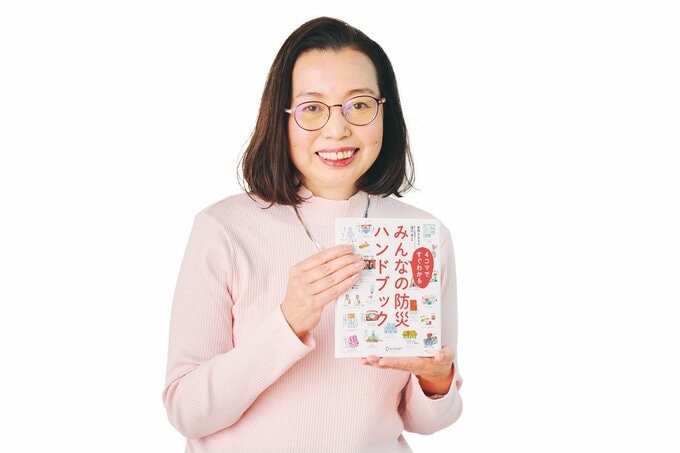 笑顔で自身の書籍を持つ草野かおるさん