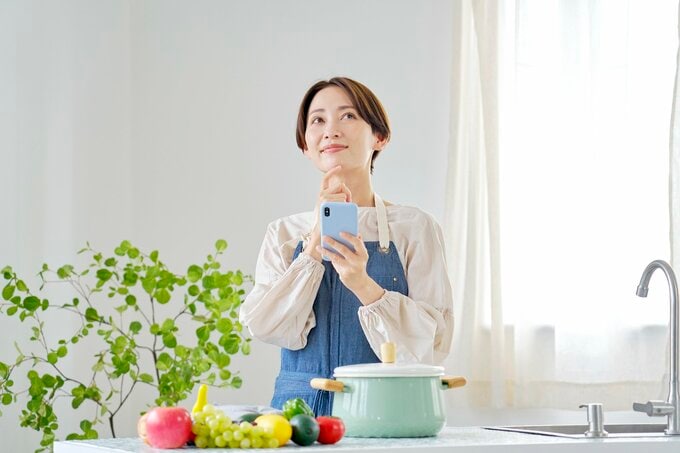 キッチンでスマホを扱う女性