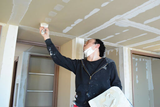 天井をパテ塗りする職人さん