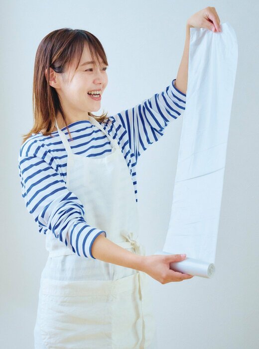 再生ポリエチレン入りごみ袋のロールを伸ばす女性