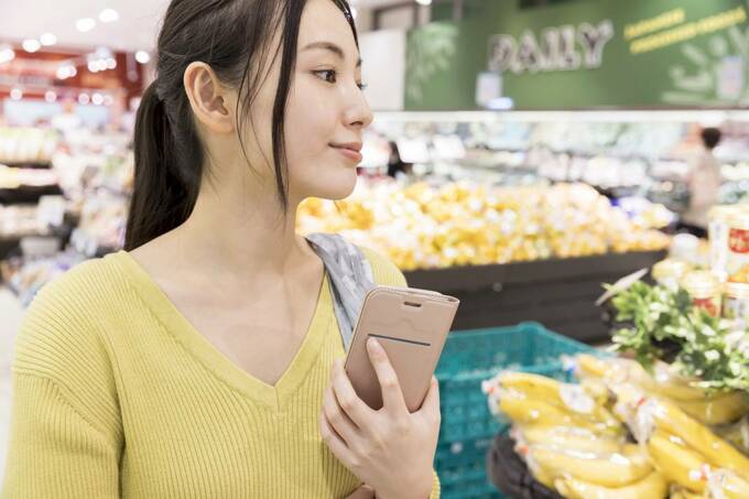 スーパーでスマホを持つ女性