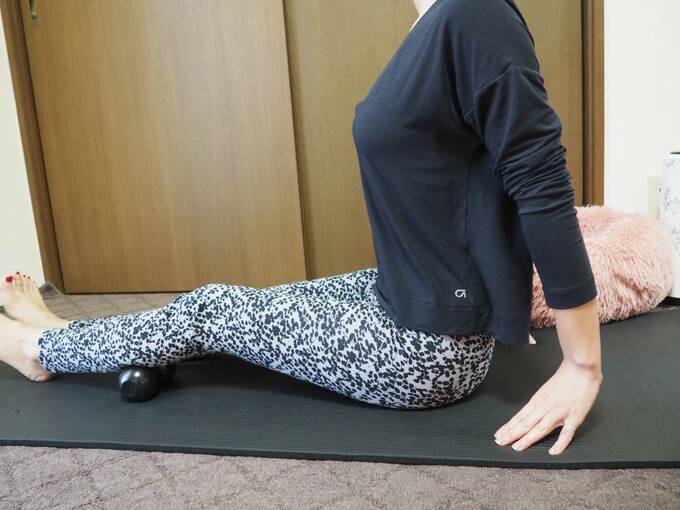 ふくらはぎにツボ押しを置いて座る女性
