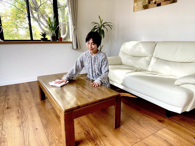 リビングのローテーブルを布巾でふく女性