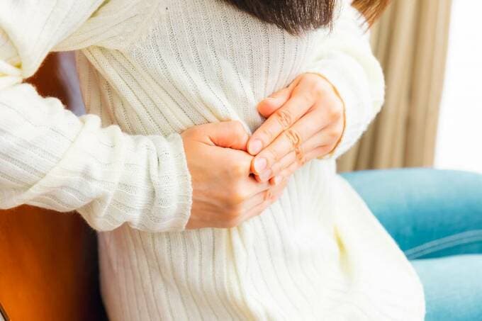 お腹をおさえる女性