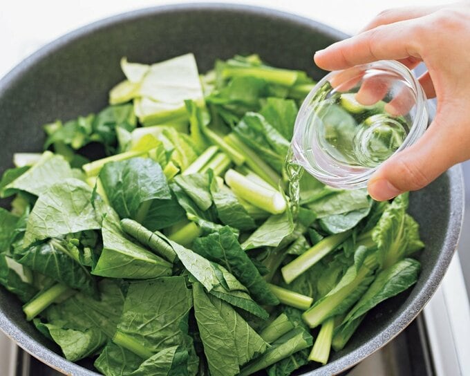 野菜が入ったフライパンに水を加える様子