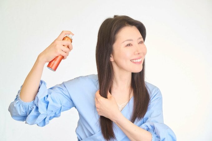 髪にスプレーをかける女性