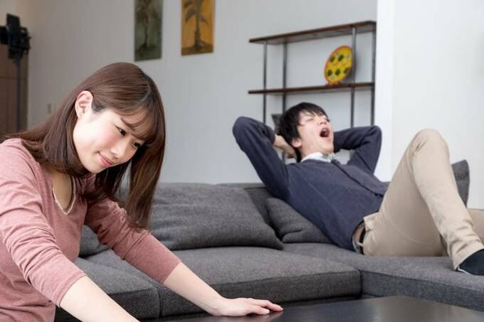 ソファであくびをする男性とテーブルに手をつく女性