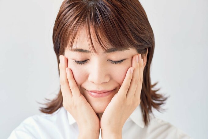 頬を両手でおさえる女性