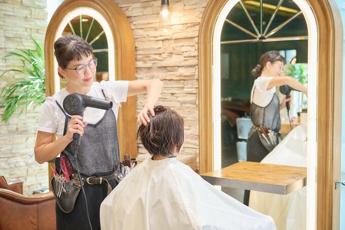 女性の髪を乾かす美容師