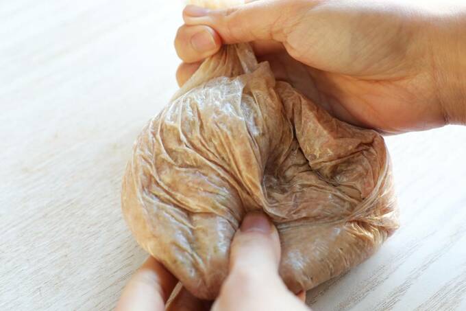 ポリ袋に入った豚ひき肉、タマネギをもむ