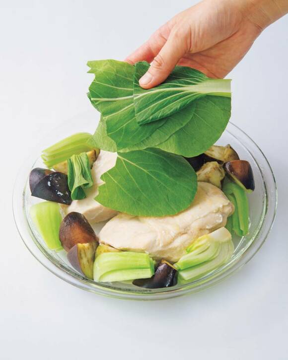 鶏肉の上にチンゲンサイをのせる様子