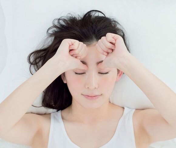 親指で眉根を押し込む