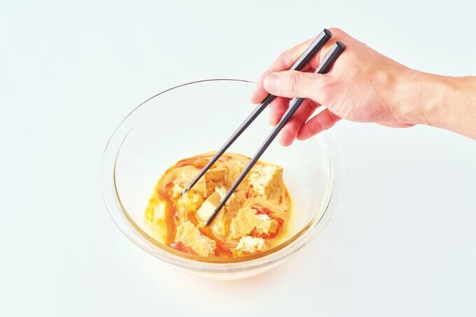 ボウルに入れた卵と厚揚げを箸で混ぜる