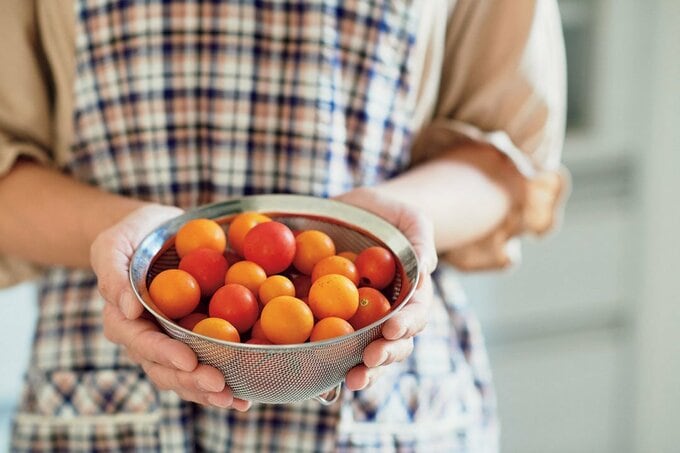 トマトが入った器を持つ女性