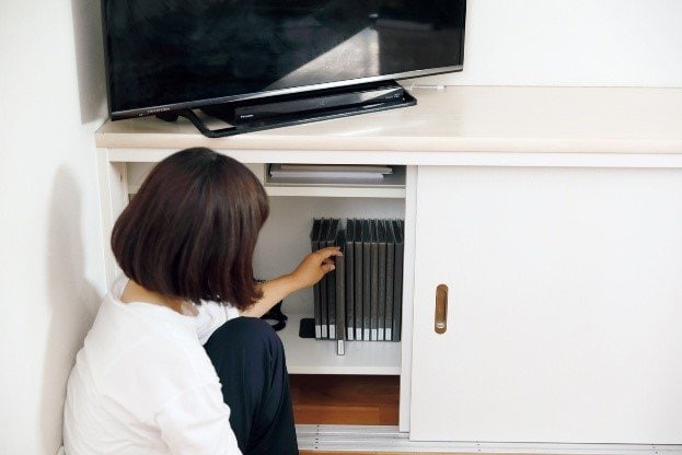 テレビボード内を整理する女性