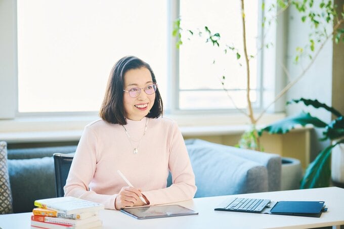 笑顔でペンを握る草野かおるさん