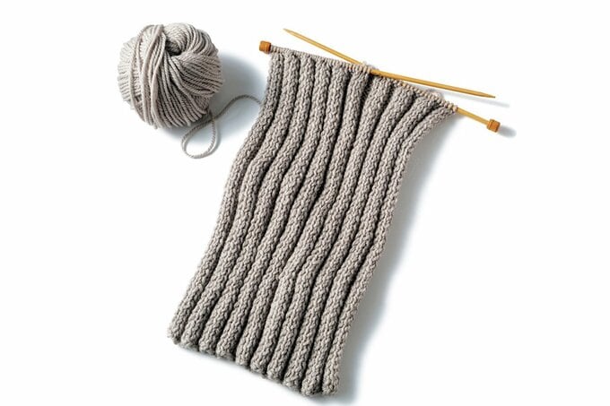 ベージュ―の毛糸玉と、編んでいる途中の編み物