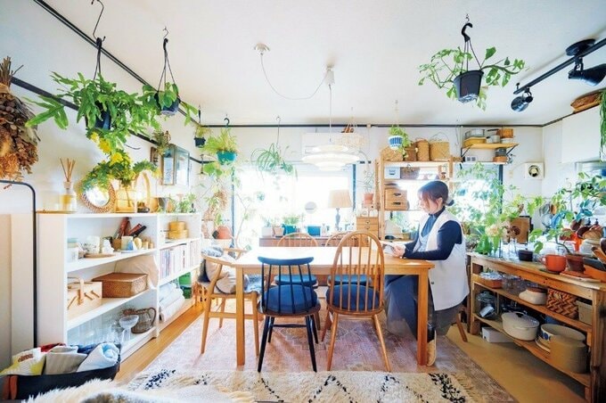 雑貨やグリーンにあふれる部屋で読書をする女性