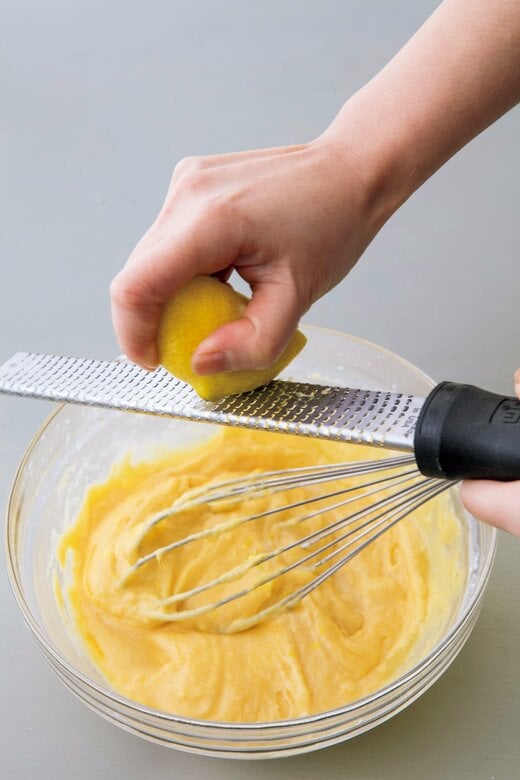 ボウルに入った生地にレモンを削り入れる様子