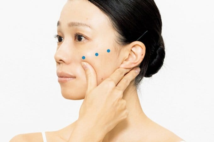 頬骨に親指を当てる女性