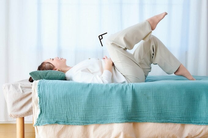 ベッドに寝ながらストレッチをする女性