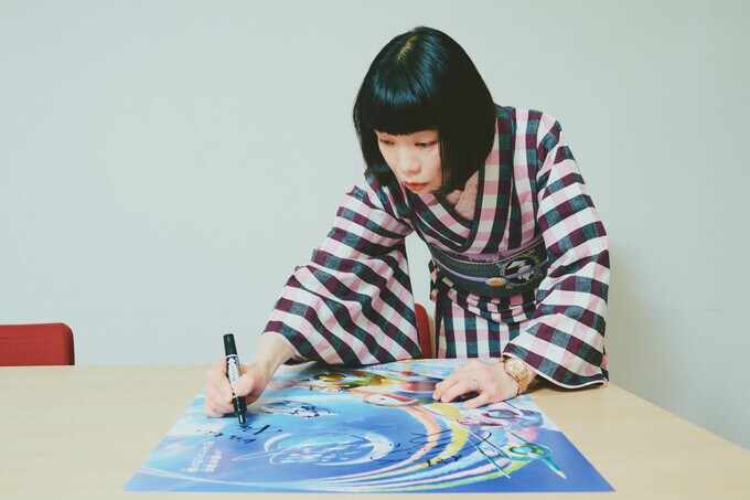 プレゼントのポスターにサインをする水田さん