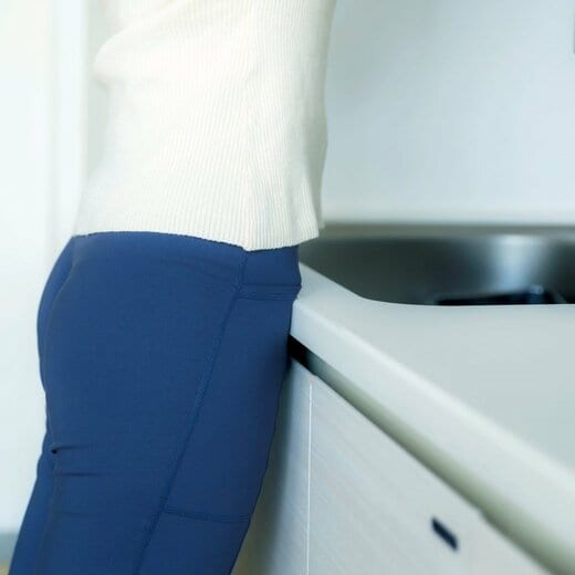 おなかを流し台につけて洗い物をしている人