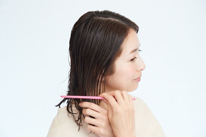 コームでトリートメントをのばす女性