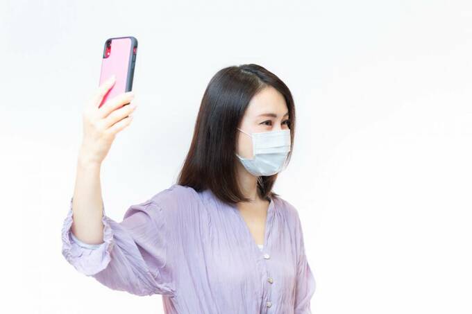 スマホで髪を撮影する女性