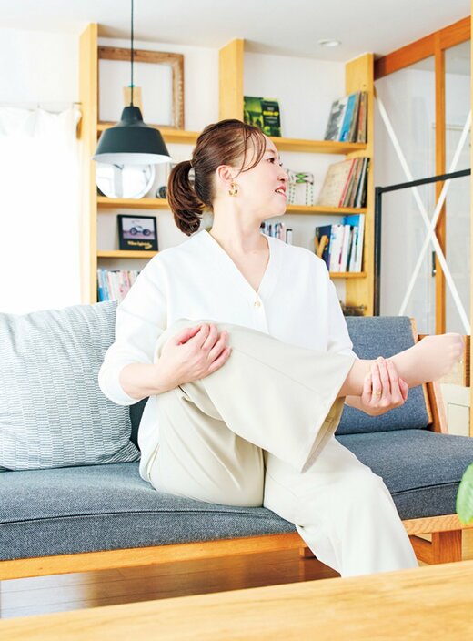 ソファに座って足のストレッチをする女性