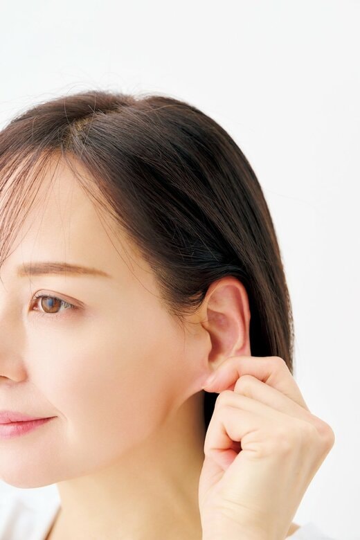 耳たぶを親指と人さし指ではさむ女性