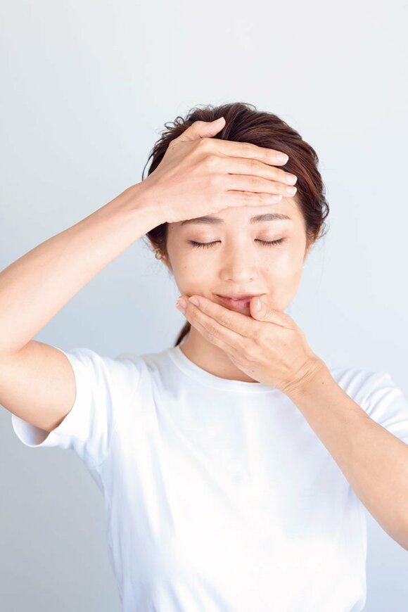 両手で顔をおさえる女性