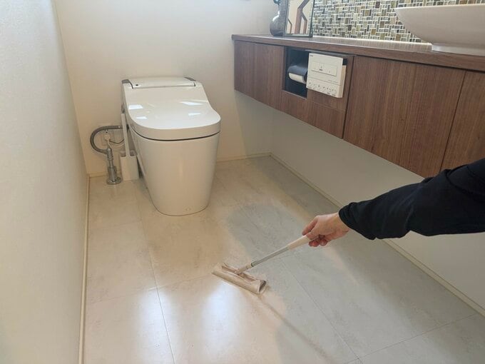 トイレの床をフローリングワイパーで掃除している