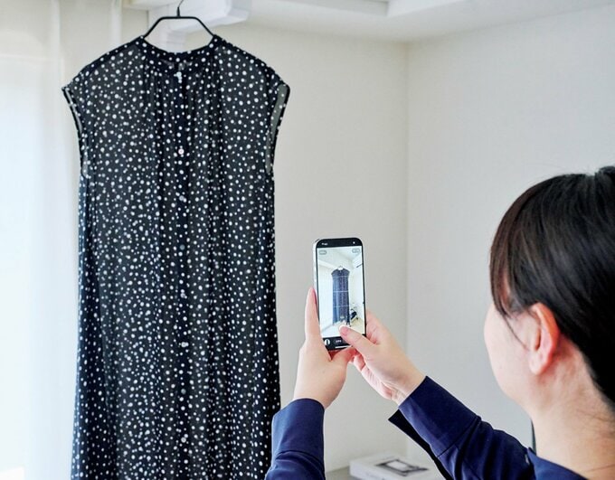 ワンピースの写真をスマホで撮る女性