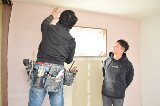 クロスを貼る職人さんの作業に見とれるコジマジックさん