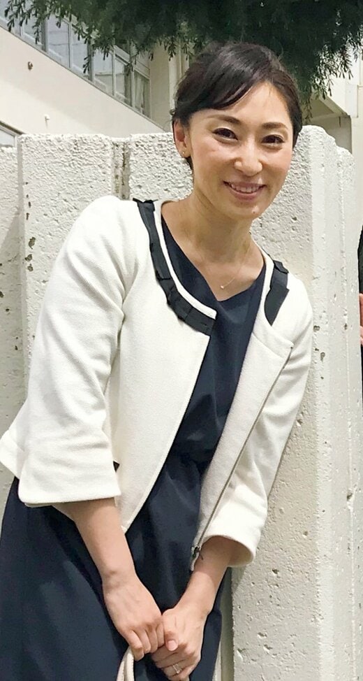 紺のワンピースに白のジャケットを着た女性