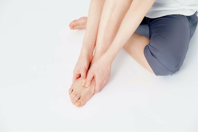 両手で足の甲のツボを押す様子