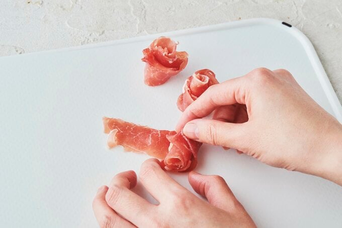 生ハムをバラの花の形に巻いているところ