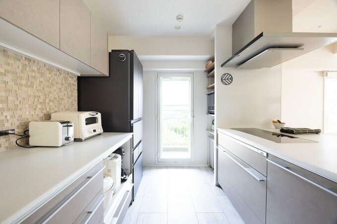 ゆったりとした通路幅のキッチン内部。Lクラスでまとめた収納スペースにはモザイクタイルをはり、遊び心をプラス